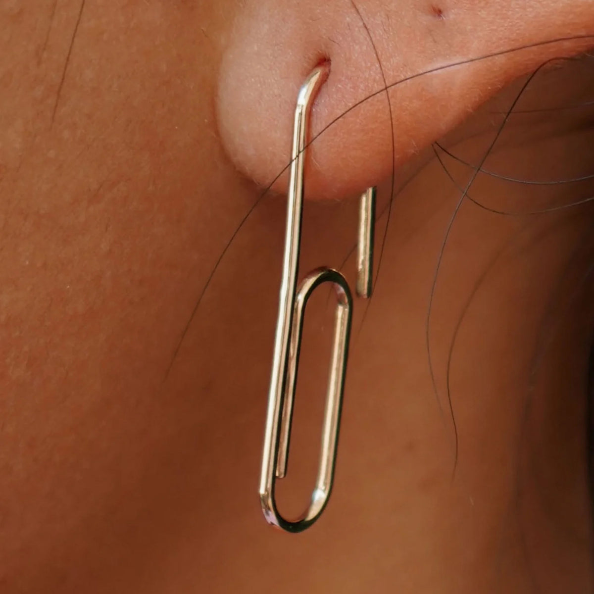 Close up view of a model's ear wearing a Champagne gold Not A Paper Clip Earring