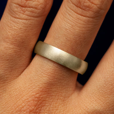 A models hand wearing a 14k champagne gold curvy matte band