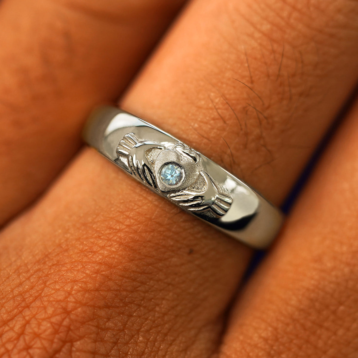Close up view of a model's fingers wearing a 14k champagne gold aquamarine Gemstone Claddagh Band