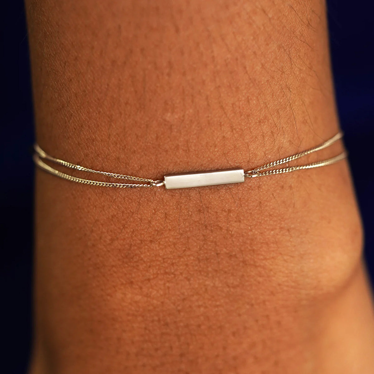 A model's wrist wearing a solid champagne gold Bar Bracelet