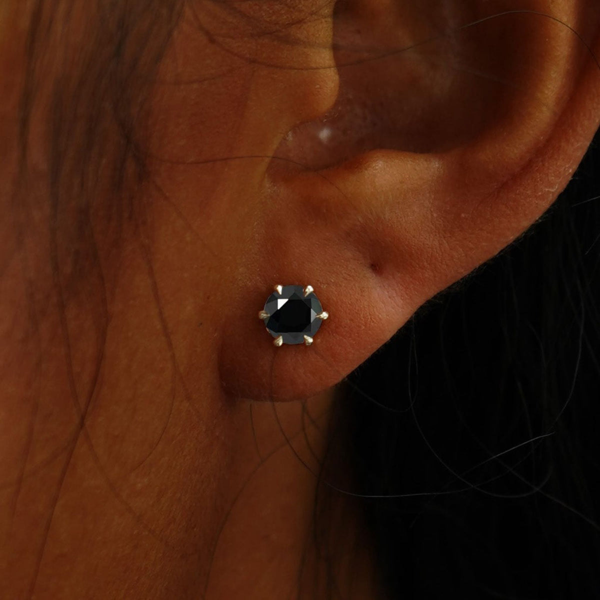 Close up view of a model's ear wearing a champagne gold black 5mm Moissanite Earring
