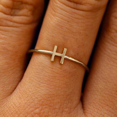 Close up view of a model's fingers wearing a 14k champagne gold block initial Ring with the letter H
