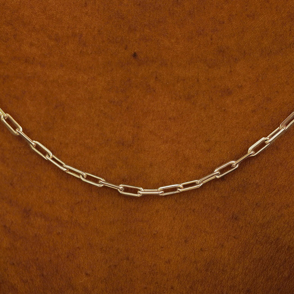 Close up view of a model in a white shirt wearing a solid champagne gold Butch Chain