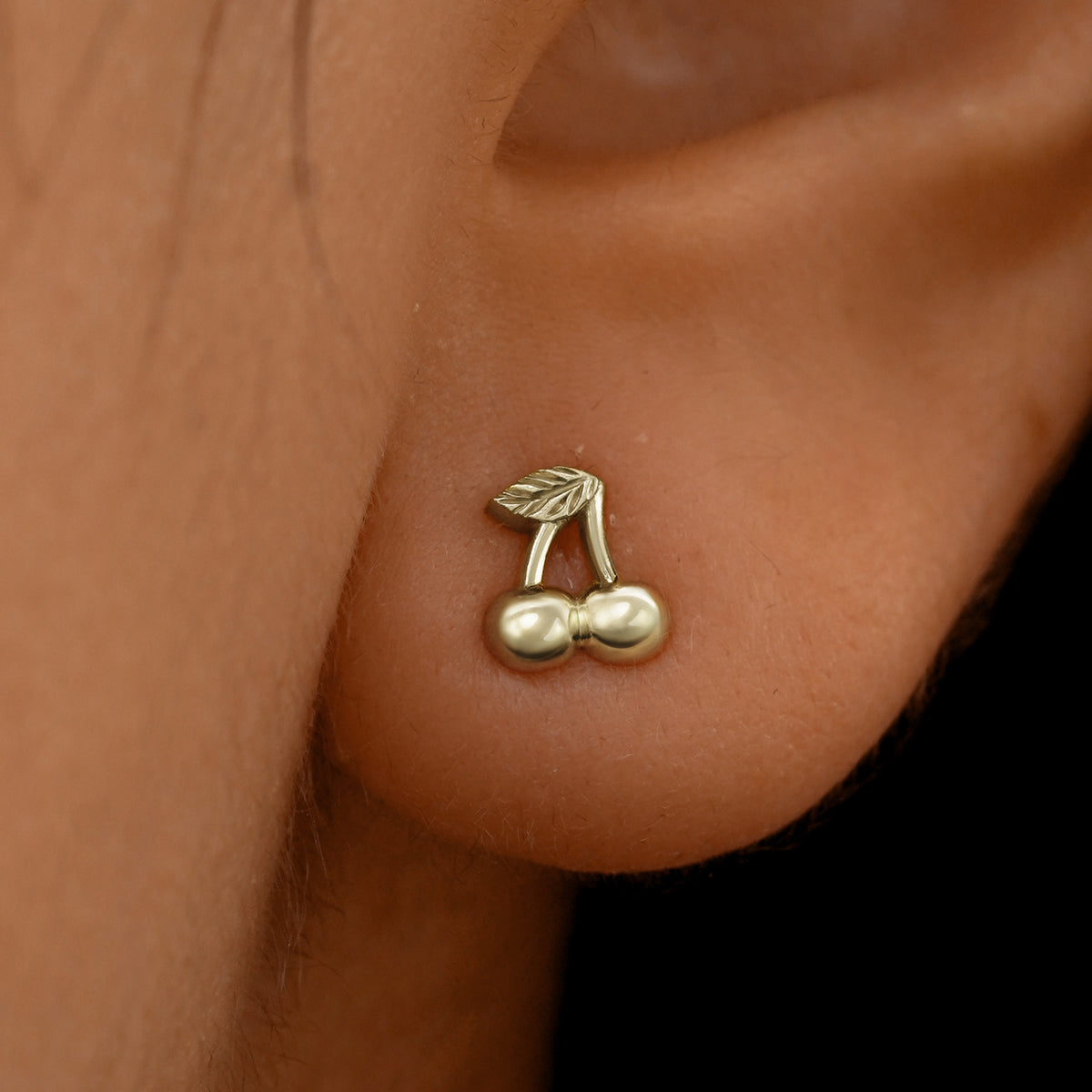 Close up view of a model's ear wearing a 14k champagne gold Cherry Earring