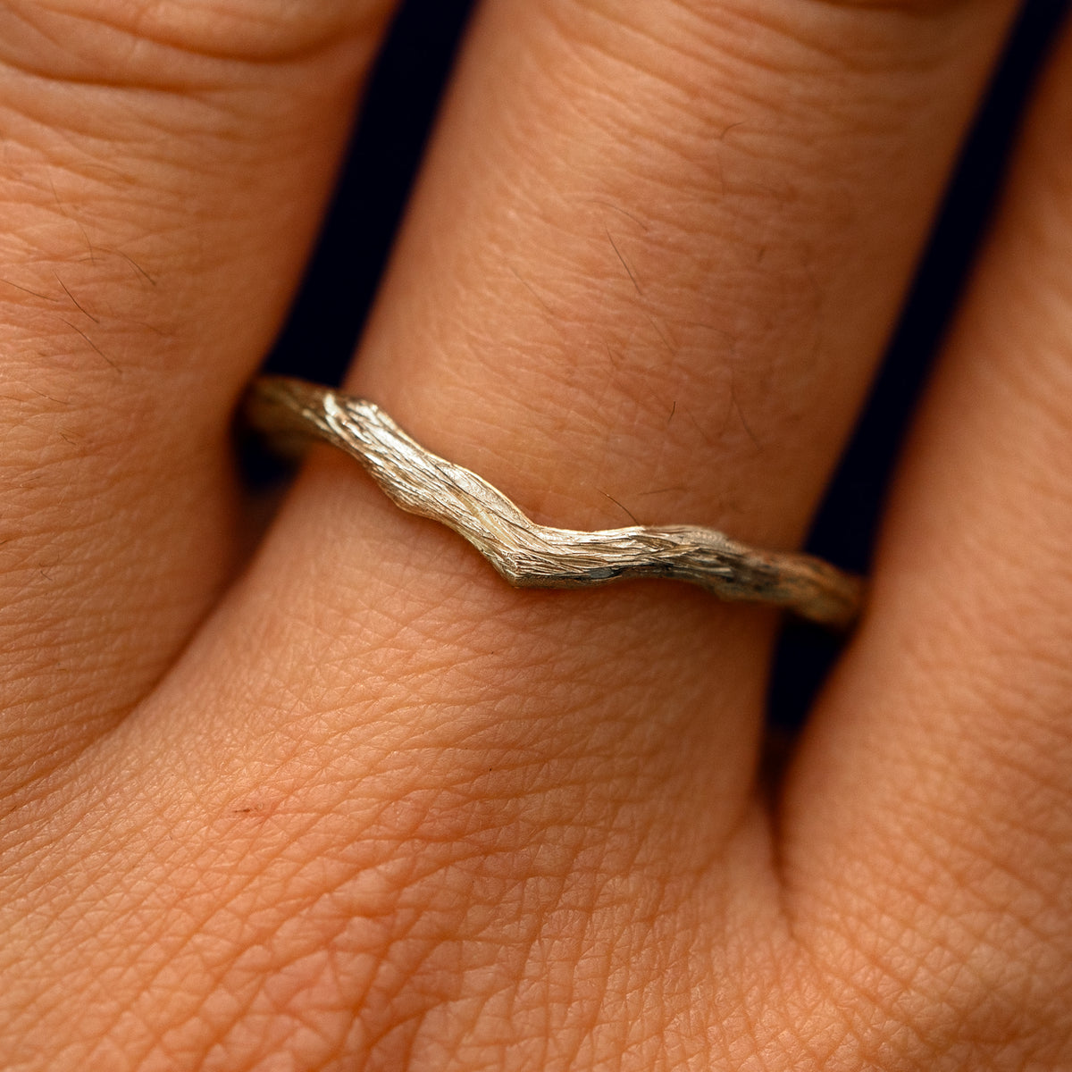 Close up view of a model's fingers wearing a 14k champagne gold Chevron Branches Band
