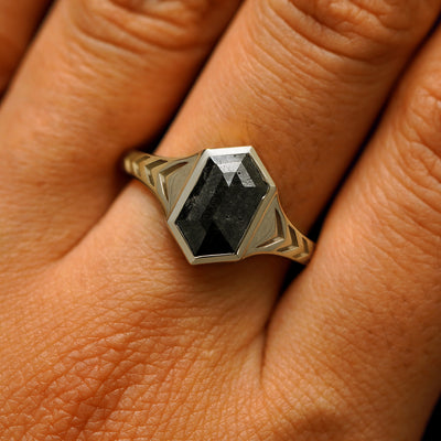 Close up view of a model's fingers wearing a 14k champagne gold elongated hexagon black diamond engraved chronos ring