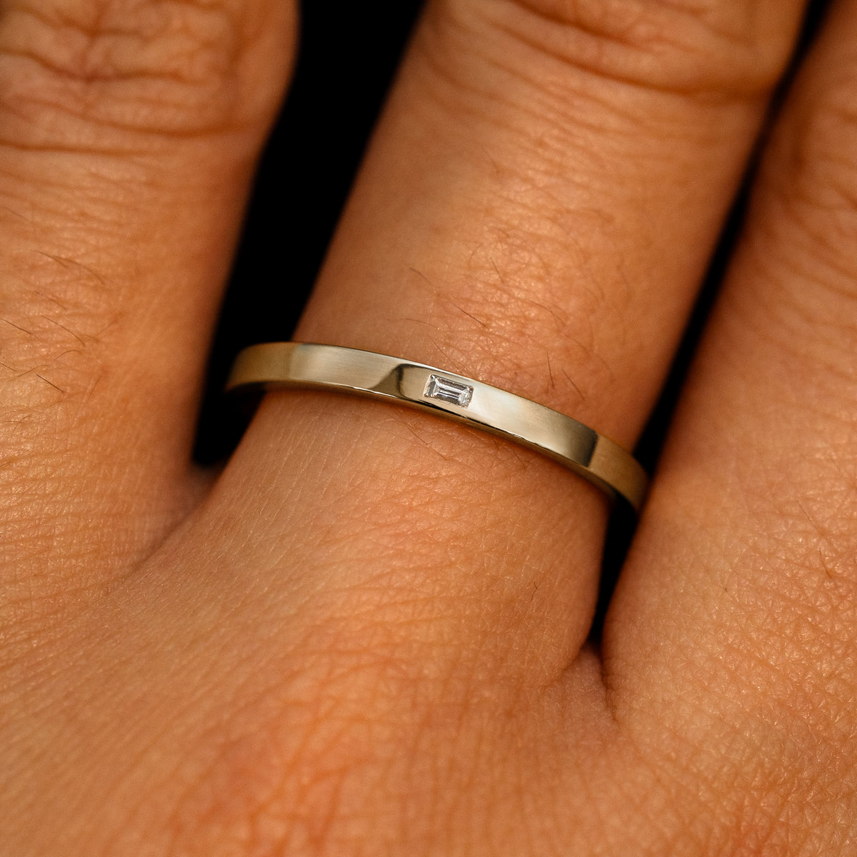 A 14k champagne gold Flush Set Baguette Diamond Ring on a model's finger