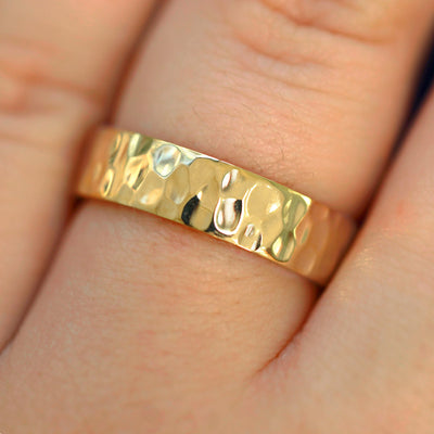 Close up view of a model's fingers wearing a 14k champagne gold Industrial Hammered Band