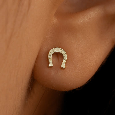 Close up view of a model's ear wearing a 14k champagne gold Horseshoe Earring