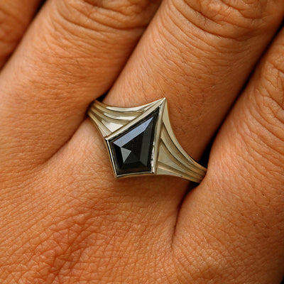 Close up view of a model's fingers wearing a 14k champagne gold kite black diamond engraved journey ring