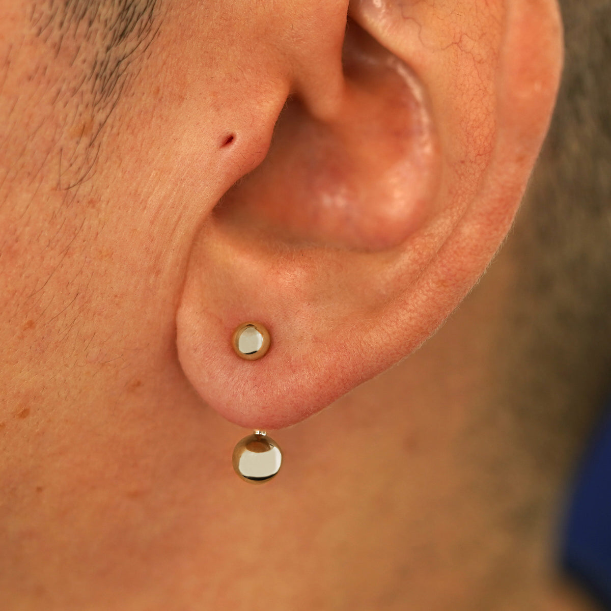 Close up view of a model's ear wearing a 14k champagne gold Large Curved Barbell through a lobe piercing