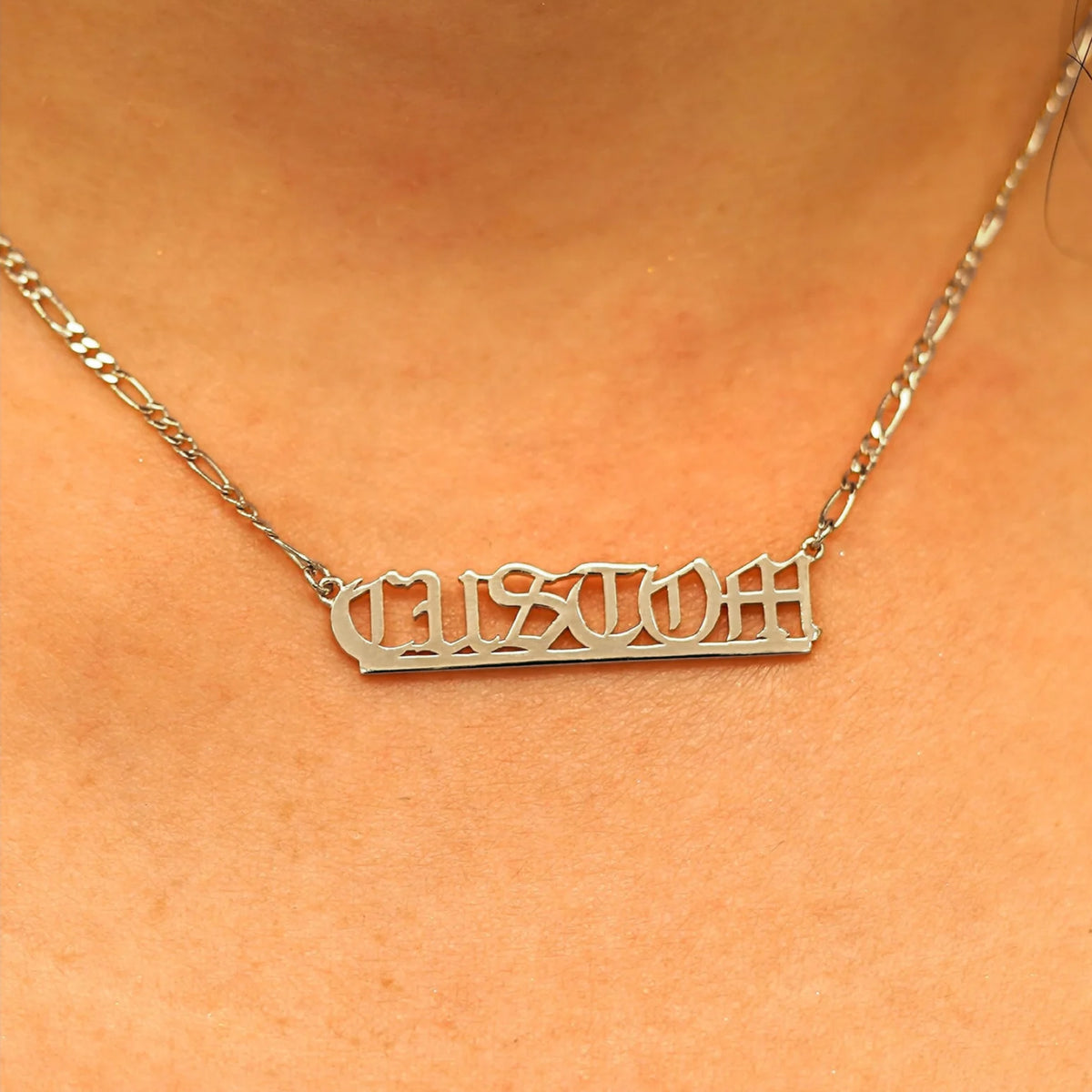 Close up view of a model's neck wearing a Medium Custom Nameplate necklace that reads the word Custom