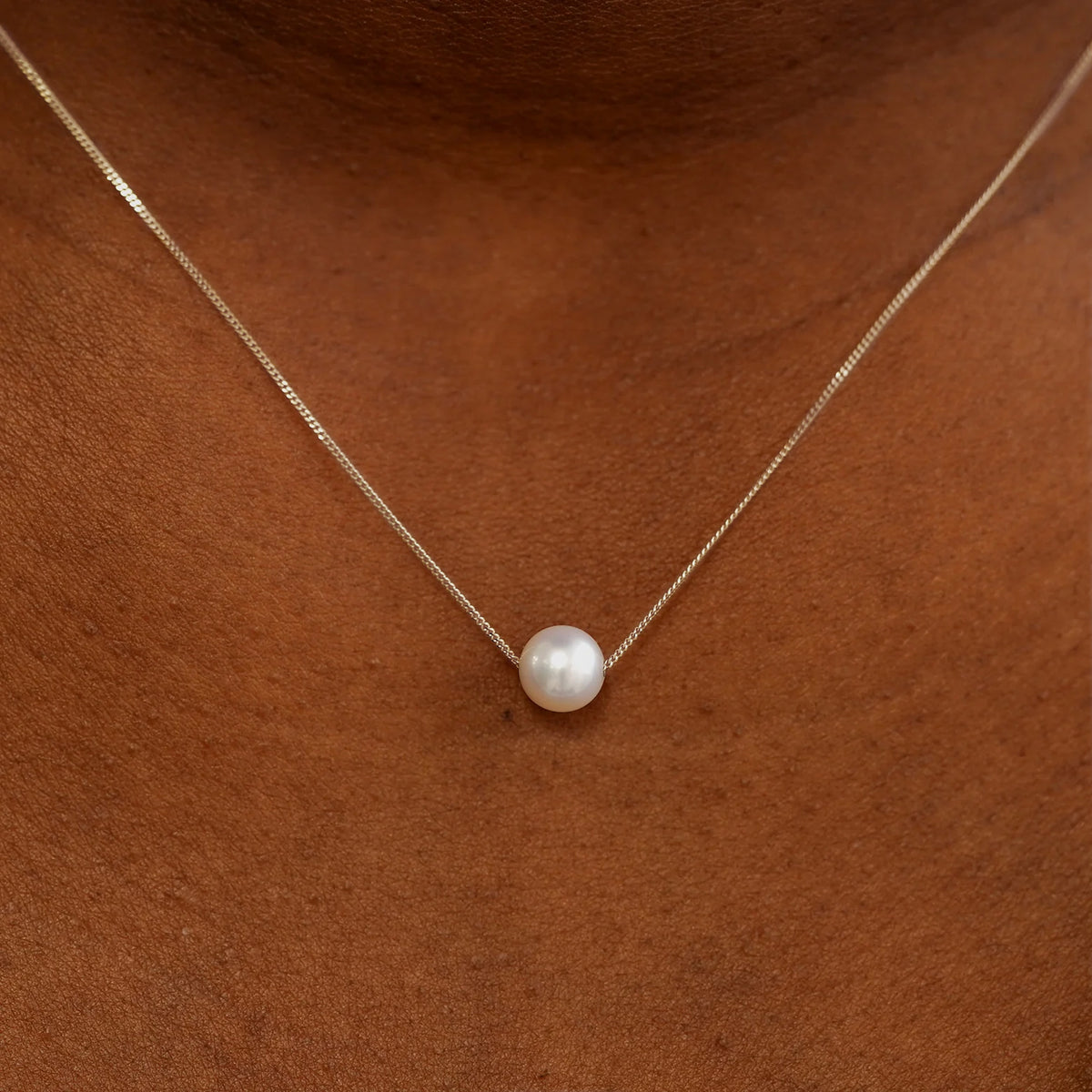 Close up view of a model's neck wearing a champagne gold Pearl Slide Necklace with a 6mm pearl