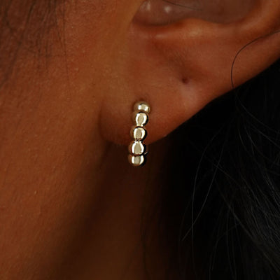 Close up view of a model's ear wearing a 14k champagne gold Mini Puffy Beaded Hoop
