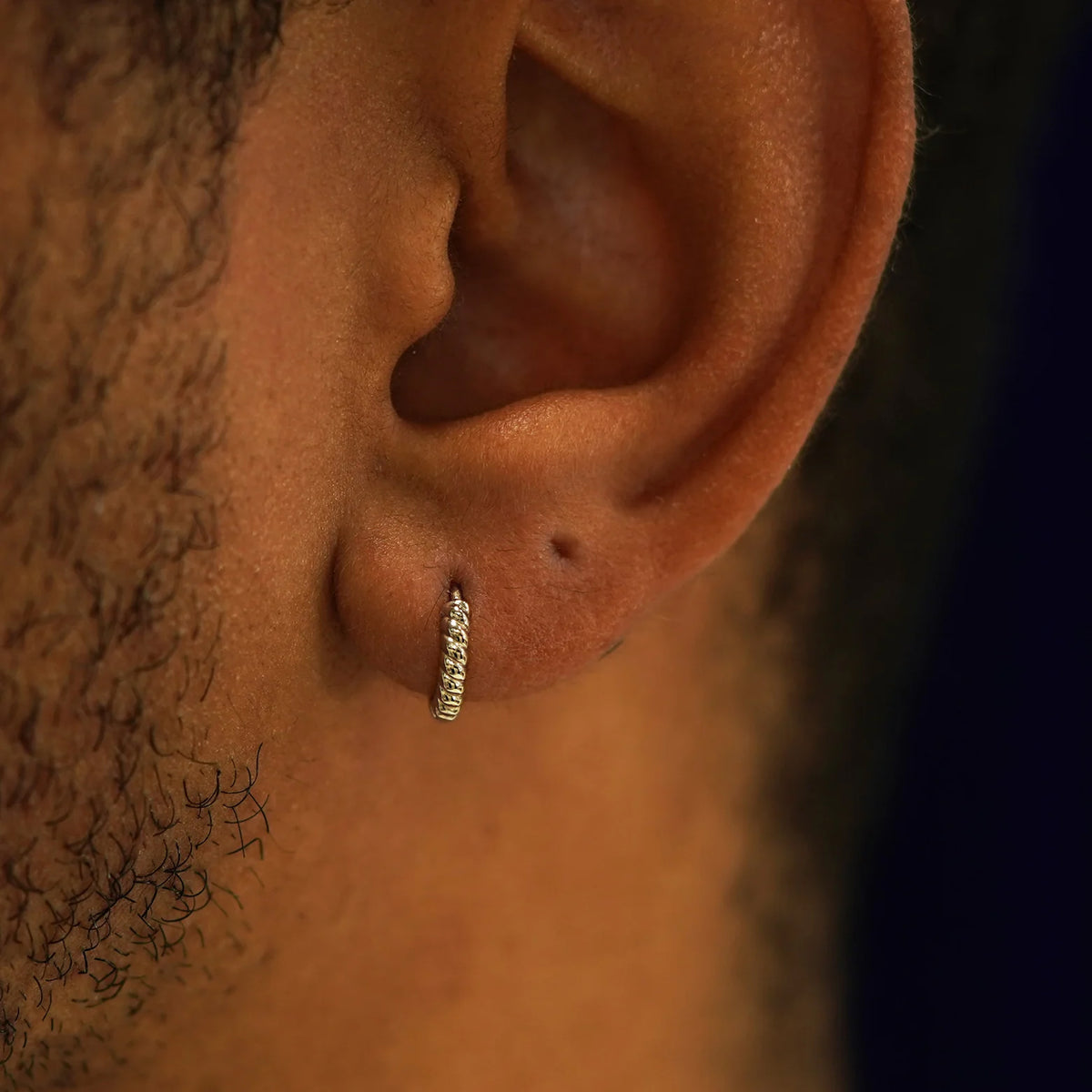 A model's ear wearing a 14k champagne gold Mini Rope Huggie Hoop Earring