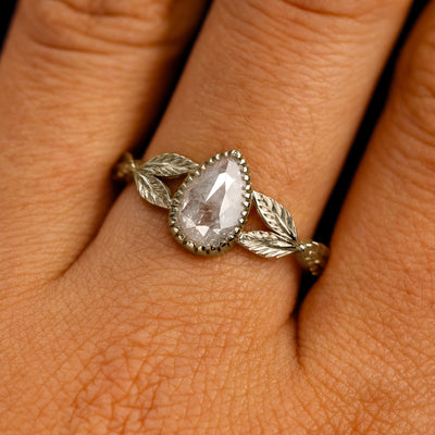 Close up view of a model's fingers wearing a 14k champagne gold Pear Salt and Pepper Diamond Leaves Ring