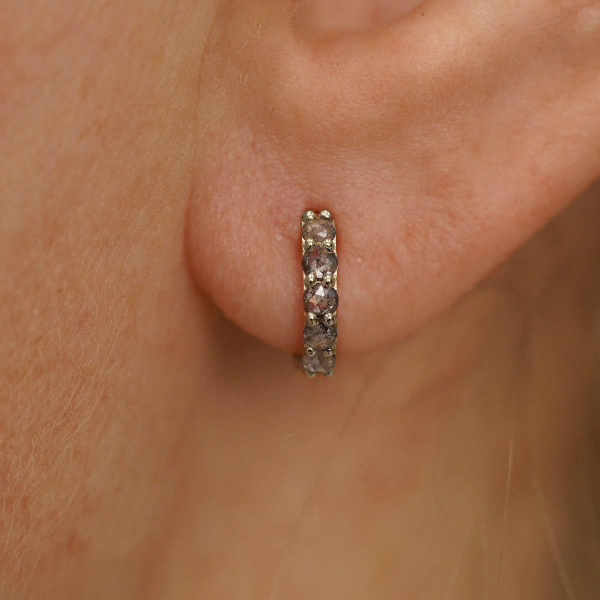Close up view of a model's ear wearing a champagne gold Mini Salt and Pepper Diamond Huggie Hoop