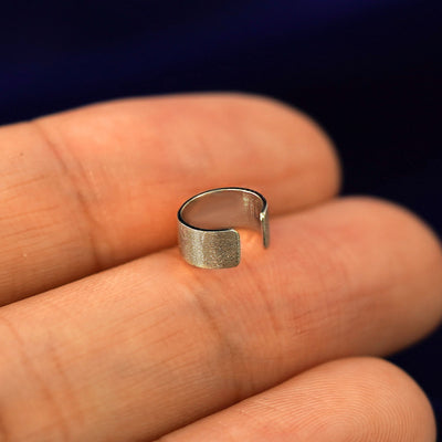 A solid champagne gold Thick Stardust Cuff earring resting on a model's fingertips