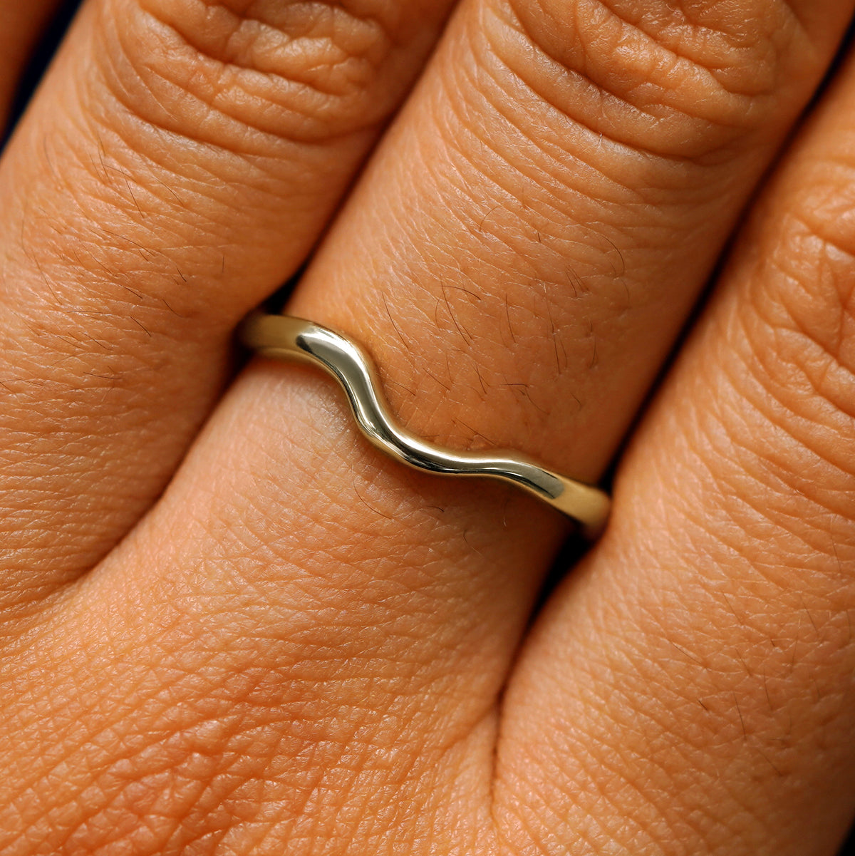 Close up view of a model's hand wearing a 14k champagne gold thin liquid band