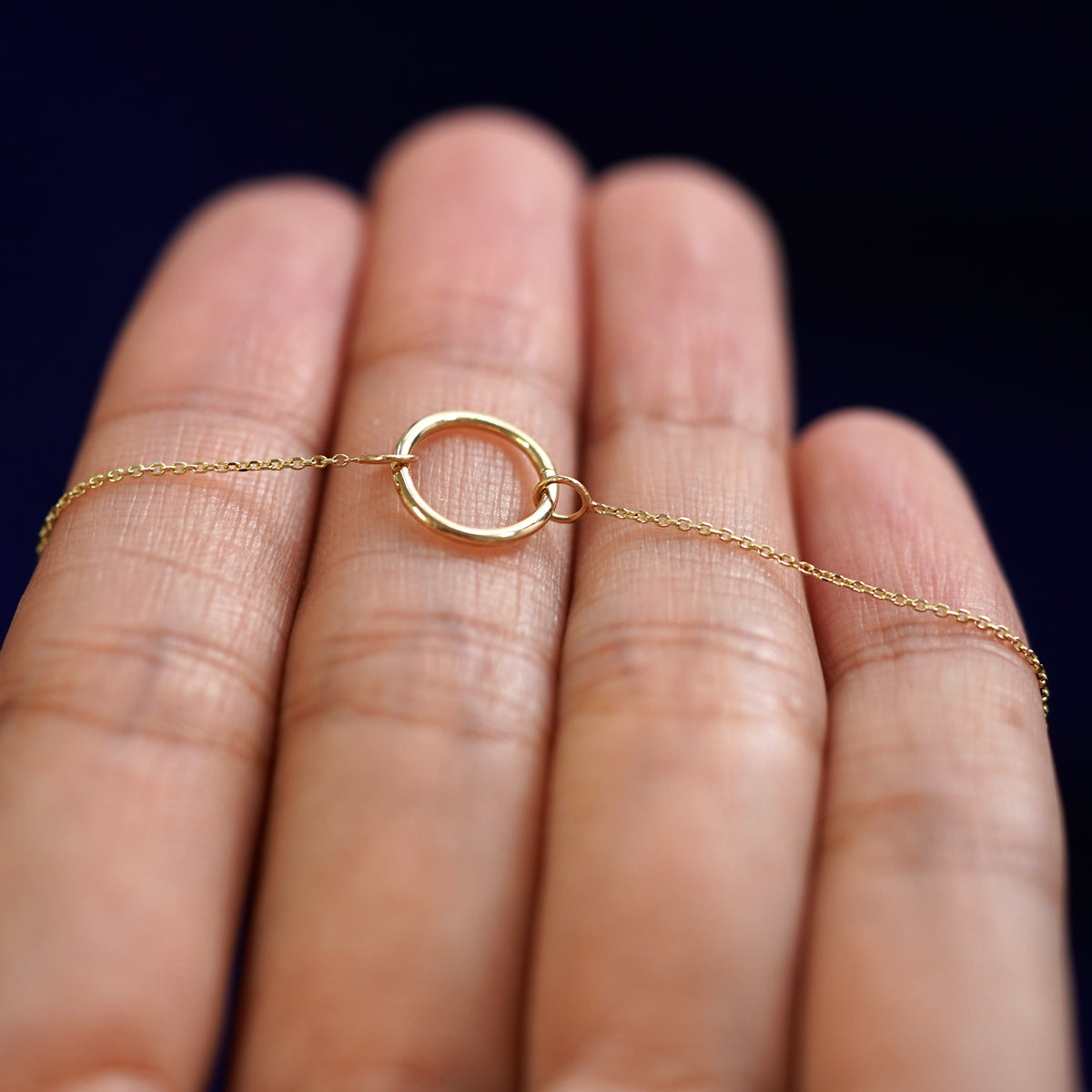 A yellow gold Lockless Cable Necklace resting on a model's fingers