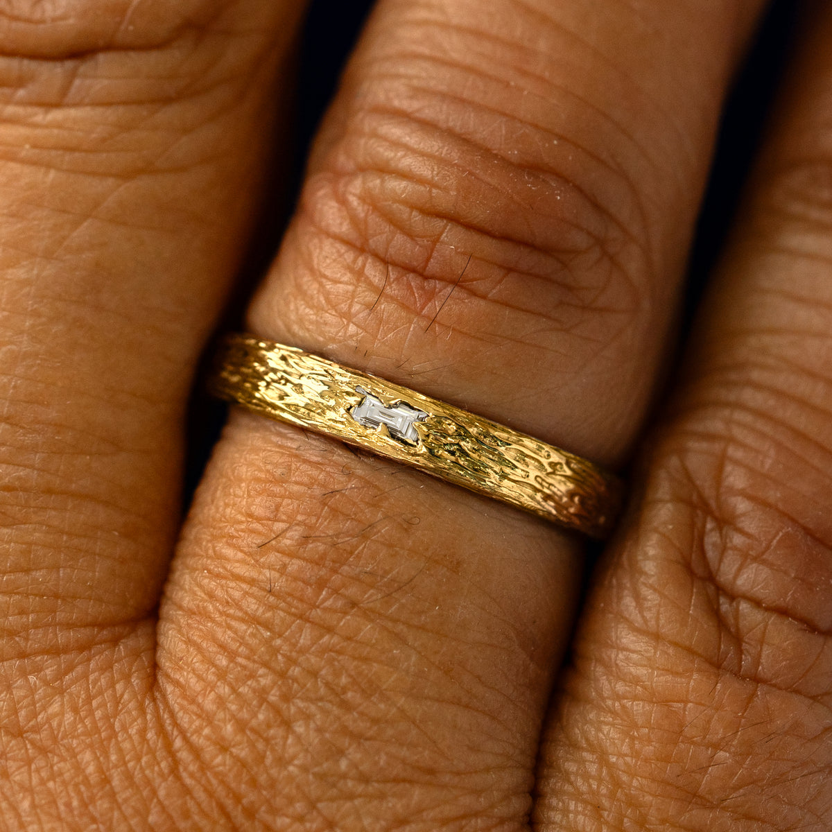 A clear baguette diamond raw band on a models finger