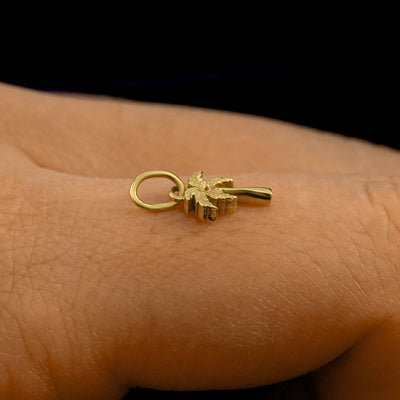 Side view of a 14k solid gold Palm Tree Charm on a model's finger to show the details and thickness of the charm