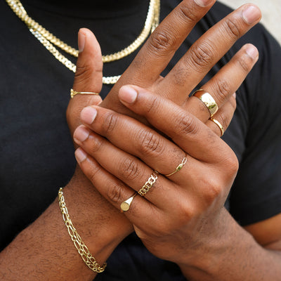 A model clasping the back of their hand while wearing various Automic Gold Jewelry
