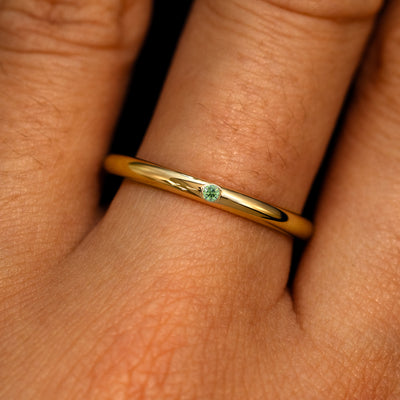A 14k yellow gold Flush Set Round Green Diamond Ring on a model's finger