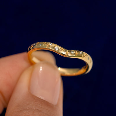 A model holding a Curvy Chevron Diamond Stars Band up to show the details of the design and the inside of the ring