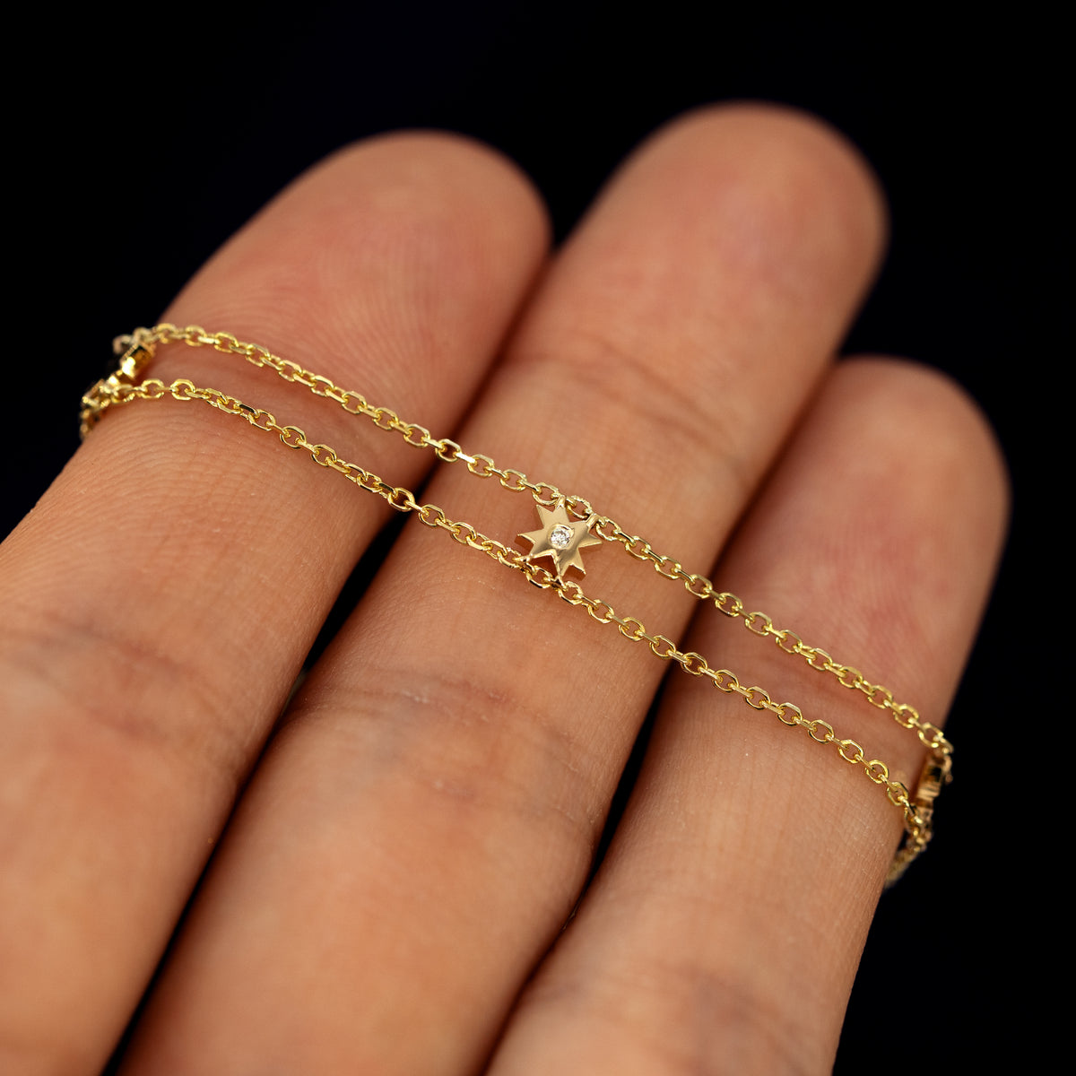 A model holding an 8 pointed star bracelet across their finger tips to show the diamond in the center star