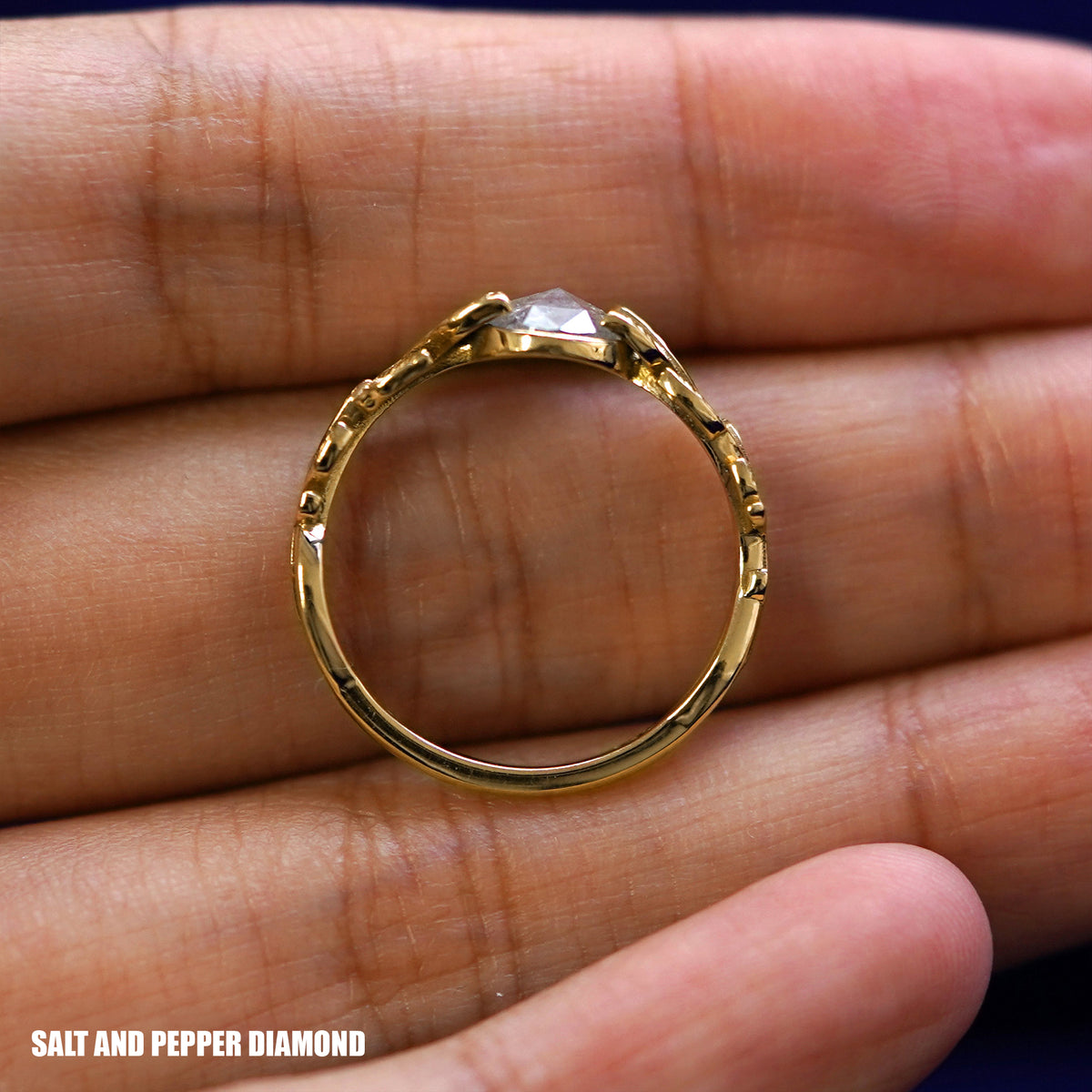 A yellow gold Salt and Pepper Leaves Ring in a model's hand showing the thickness of the band