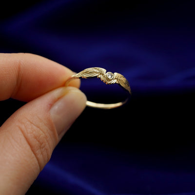 A model holding a 14k yellow gold Diamond Wings Ring tilted to show the side of the ring