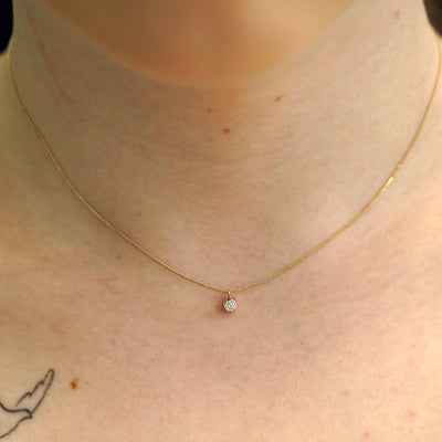 A model's neck wearing a solid 14k yellow gold Diamond necklace