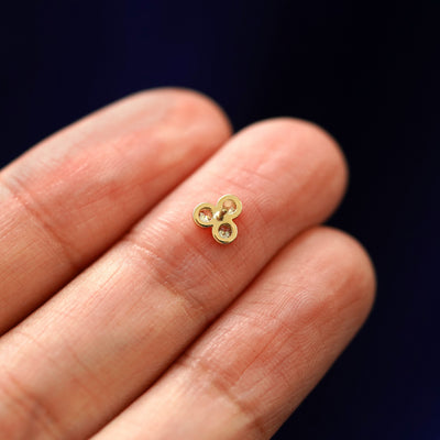 A Diamond Trio Earring laying face down on a model's finger tip to show the post without a backing