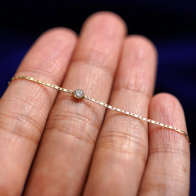 A yellow gold Diamond Bracelet resting on a model's fingers
