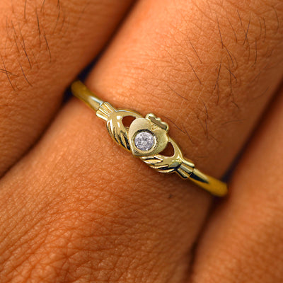 Close up view of a model's fingers wearing a 14k yellow gold diamond Thin Gemstone Claddagh Ring
