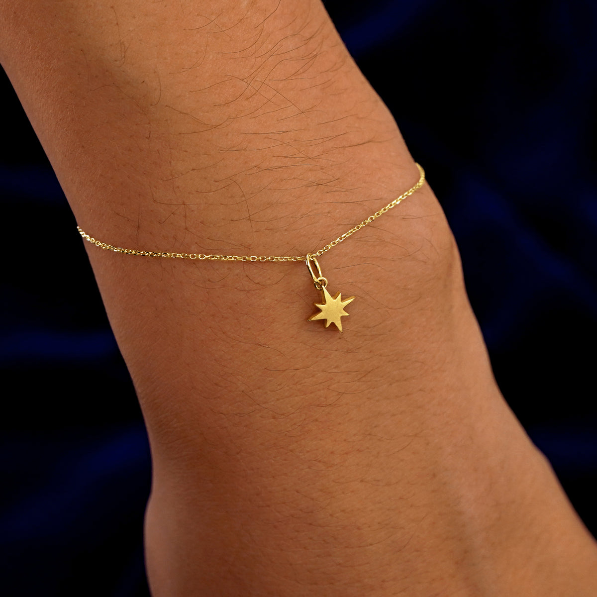 A model's wrist wearing a yellow gold Starburst Charm on a Cable Bracelet
