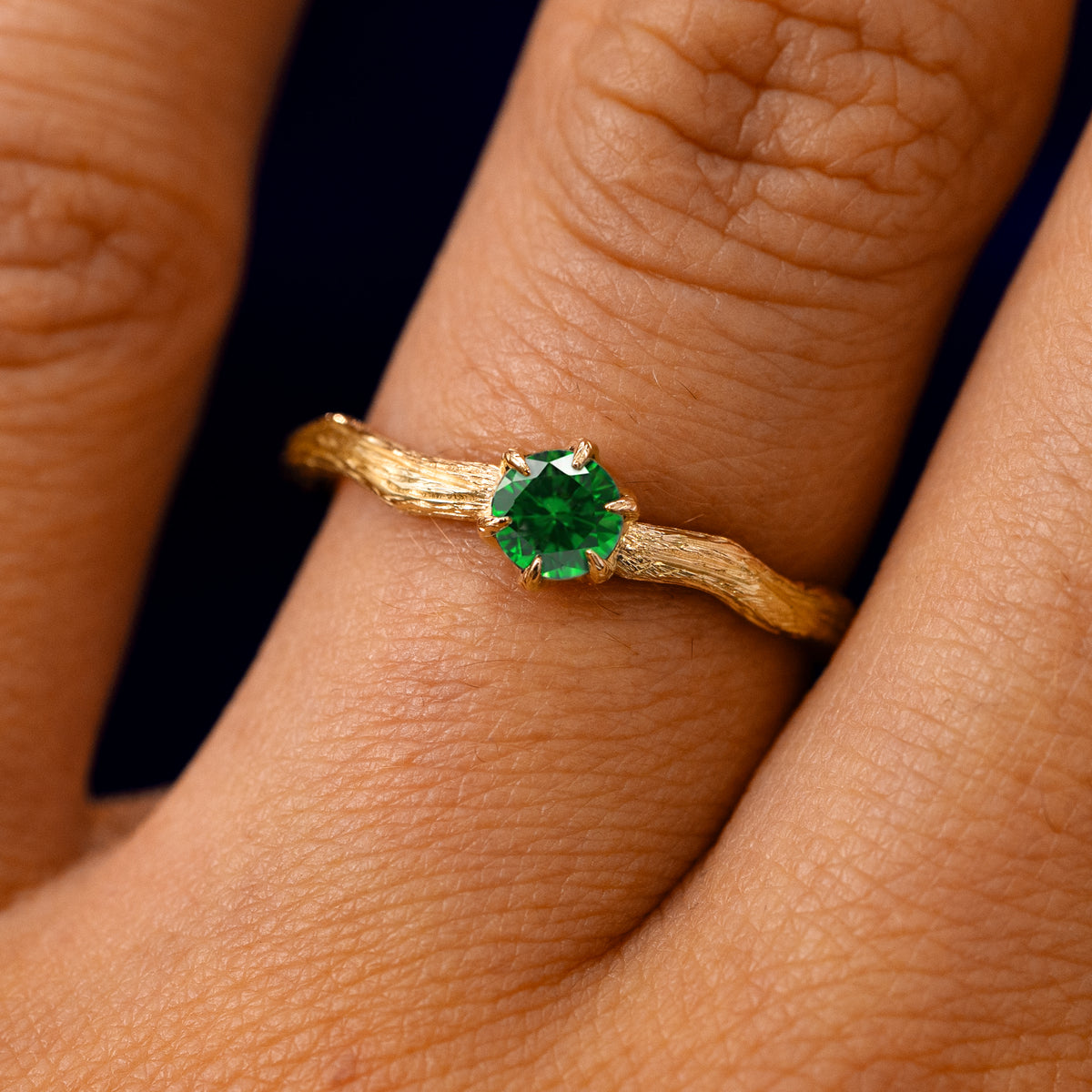 A solid 14k yellow gold Emerald Waved Branch Ring on a model's finger