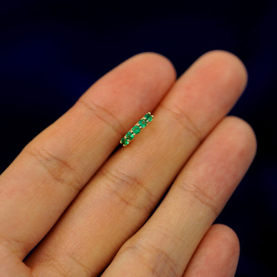 A small Emerald huggie hoop earring on a models fingers