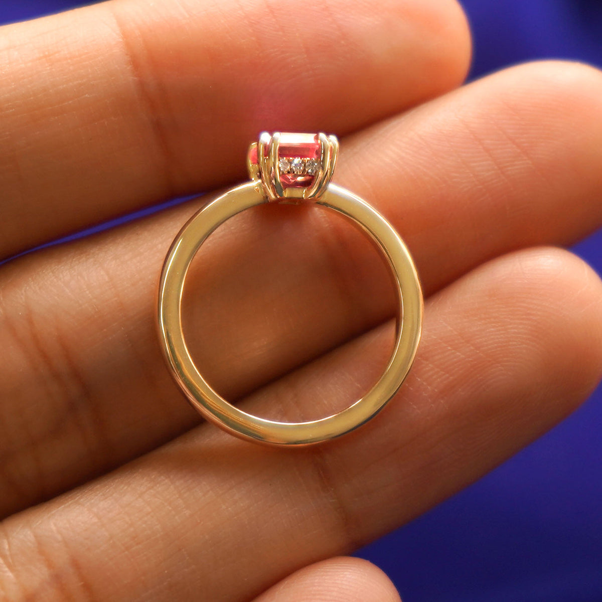 A lab pale pink sapphire ring in a model's hand showing the thickness of the band and the height of the ring