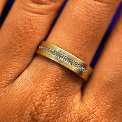 Close up view of a model's fingers wearing a 14k yellow gold Endless Salt and Pepper Diamond Band
