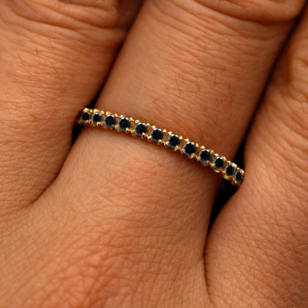 Close up view of a model's fingers wearing a 14k yellow gold Mini Petal Set Diamond Eternity Band