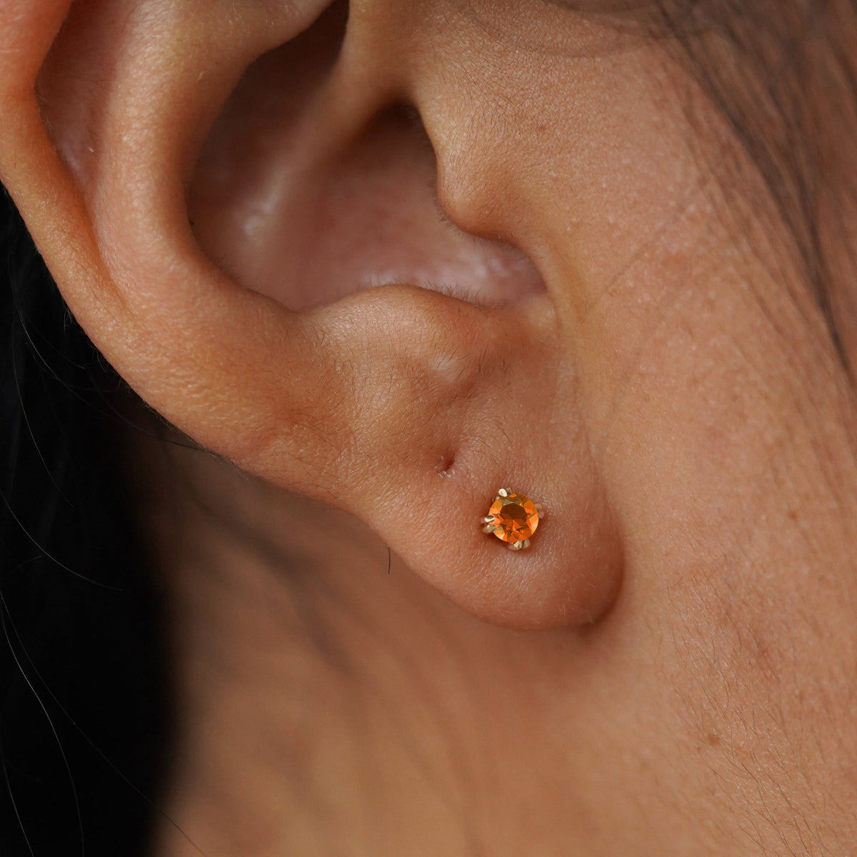 Close up view of a model's ear wearing a yellow gold orange Fire Opal Flat Back Earring