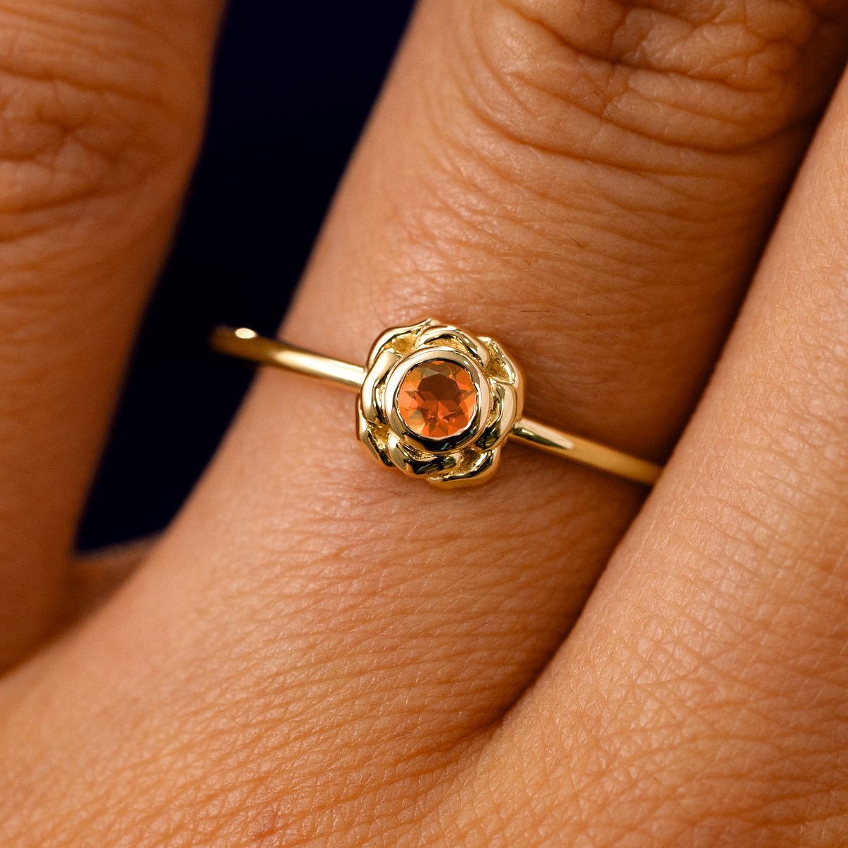 A solid 14k yellow gold Fire Opal Gemstone Flower Ring on a model's finger
