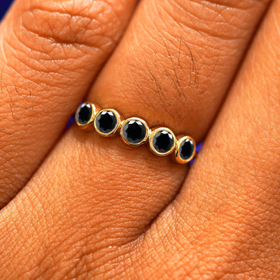 Close up view of a model's fingers wearing a 14k yellow gold Five Diamond Ring with black diamonds