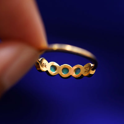 A hand holding a 5 Gemstones Ring with opals to show the underside view