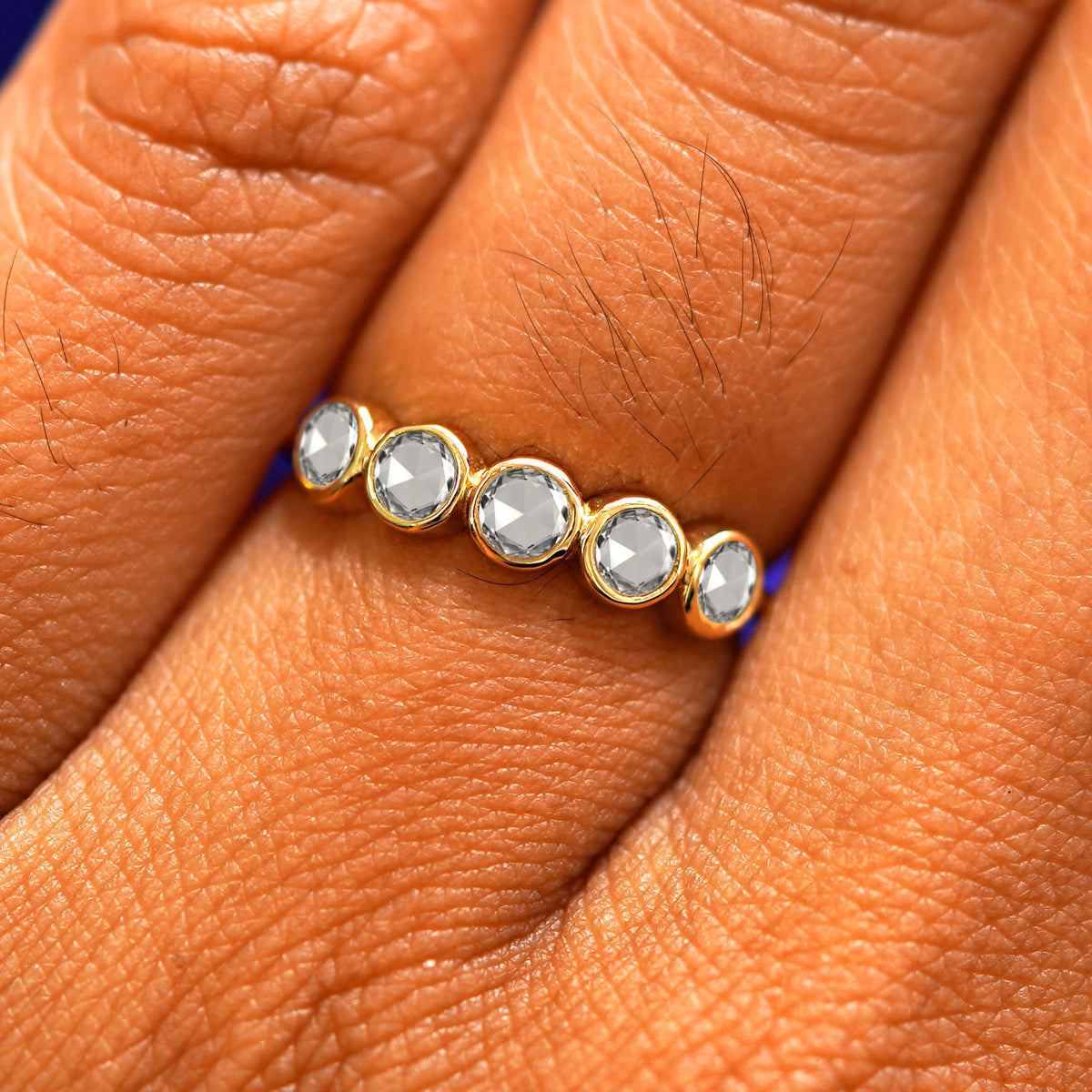 Close up view of a model's fingers wearing a 14k yellow gold Five Diamond Ring with rose cut diamonds