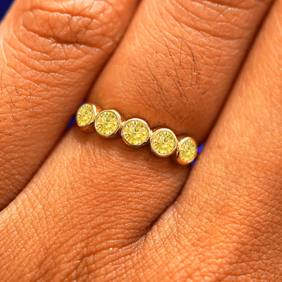 Close up view of a model's fingers wearing a 14k yellow gold Five Diamond Ring with yellow diamonds