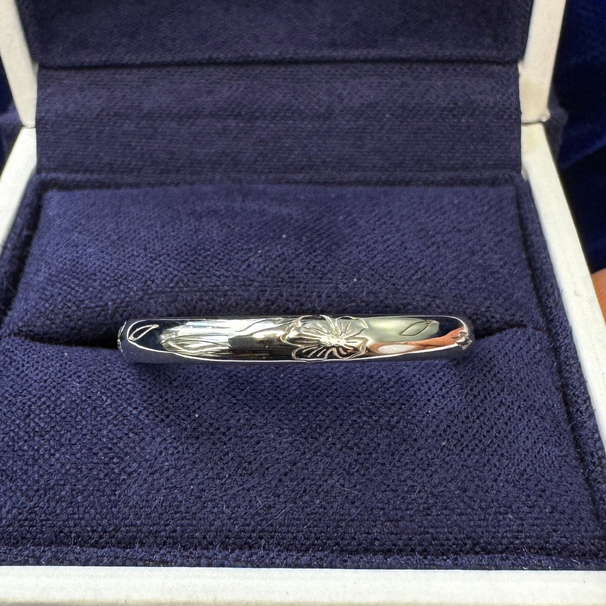 A 14k White Gold Simple Line Floral Engravings on 3mm Curvy Mirror Band Custom Ring in a blue ring box