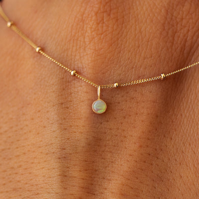 Close up view of a 14k yellow gold Gemstone Necklace on Beaded Essential Chain draped across the back of a model's hand